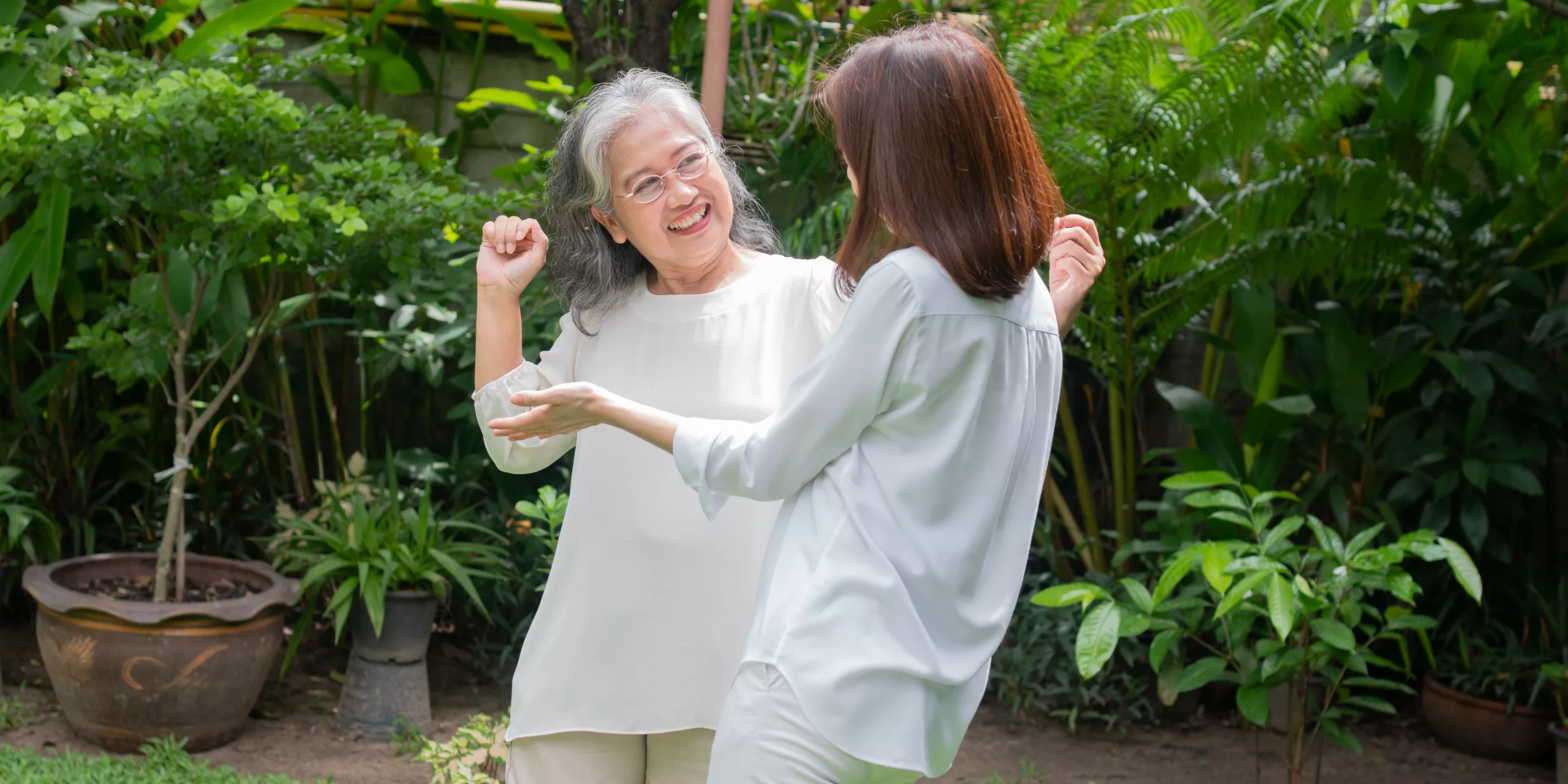 An old elderly Asian woman and dance in the backyard with her da