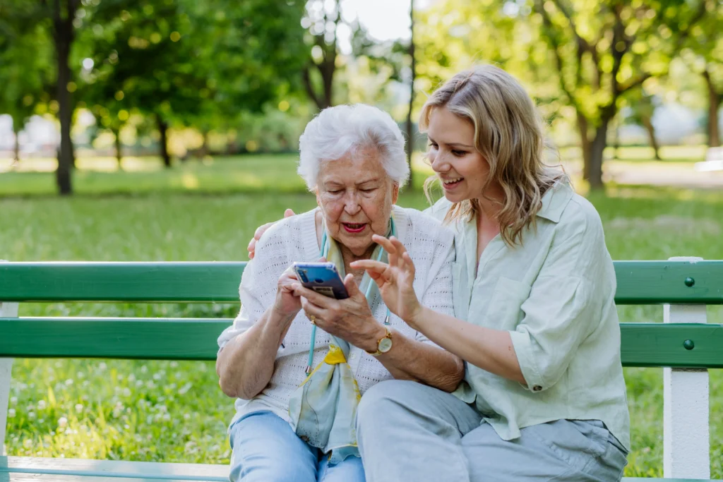Family caregiver helping an older woman use her phone to research Medicaid home care options in New York
