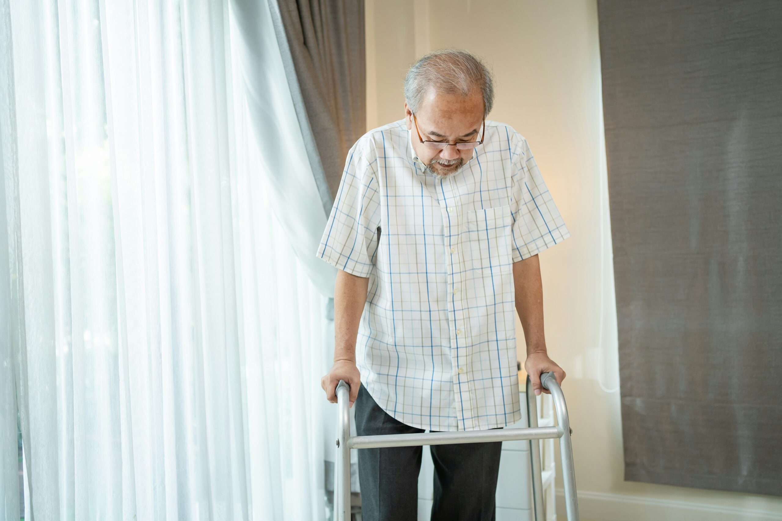 Senior man walking with a walking frame at home